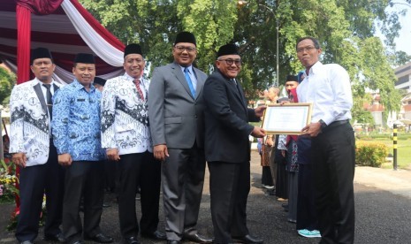 Guru SMA Islam Dian Didaktika Cinere Depok, Pratik Murwatno, saat menerima penghargaan guru berprestasi dari Walikota Depok Mohammad Idris di upacara peringatan Hari Guru Nasional (HGN) di Lapangan Balai Kota Depok, Rabu (28/11).