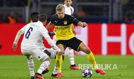 Striker Borussia Dortmund Erling Haaland diadang pemain PSG pada laga leg pertama 16 besar Liga Champions antara Borussia Dortmund melawan Paris Saint Germain di Dortmund, Jerman, Rabu (19/02) dini hari. (Martin Meissner/AP Photo)