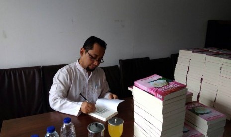 Habiburrahman El Shirazy menandatangani novel Bidadari Bermata Bening yang dibeli melalui pemesanan pre order, Ahad (30/4).