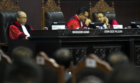 Hakim konstitusi Suhartoyo (kanan) berbincang dengan Hakim Konstitusi I Dewa Gede Palaguna (tengah), Hakim Konstitusi Wahiduddin Adams (kiri) saat memimpin sidang putusan gugatan quick count atau hitung cepat pada Pemilu serentak 2019 di Mahkamah Konstitusi, Jakarta, Selasa (16/4/2019). 