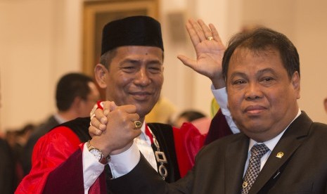 Hakim Mahkamah Konstitusi (MK) yang baru Saldi Isra (kiri) berjabat tangan dengan Ketua MK Arief Hidayat usai pelantikan hakim MK di Istana Negara, Jakarta, Selasa (11/4). 