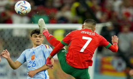  Hakim Ziyech dari Maroko (kanan) menendang bola di depan pemain Spanyol Pedri selama pertandingan sepak bola babak 16 besar Piala Dunia antara Maroko dan Spanyol, di Education City Stadium di Al Rayyan, Qatar, Selasa, 6 Desember 2022.