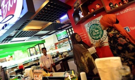  Wakil Direktur LPPOM MUI Pusat Osmena Gunawan (kedua kanan) menempelkan stiker sertifikasi halal di restoran siap saji Sushi Bar, Jakarta, Kamis (6/2).     (Republika/ Tahta Aidilla)