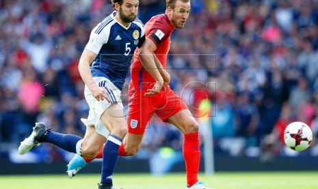 Harry Kane (kanan) dari Inggris berebut bola dengan pemain Skotlandia Charlie Mulgrew dalam laga kualifikasi Piala Dunia 2018 zona Eropa di Hampden Park, Glasgow, Sabtu (10/6) waktu setempat. Pertandingan itu berakhir 2-2. 