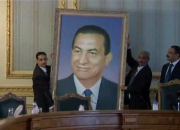 Petugas menurunkan foto Hosni Mubarak di Gedung Kabinet, di Kairo, Februari lalu.