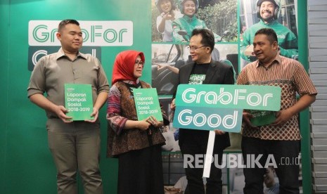 Head of Public Affairs Grab Indonesia,Tri Sukma Anreianno (berjas hitam) berbincang dengan Kepala Dinas Perdagangan dan Perindustrian Kota Bandung Elly Wasliah (kedua kiri) saat penyerahan laporan secara simbolis dampak sosisal ekonomi Grab Indonesia, Kamis (24/10).