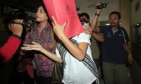 Heather Mack, covering her face, is led to a hospital for a medical check by Indonesian police officers in relation to the death of her mother Sheila von Wiese-Mack in Bali, Indonesia, Friday, Aug. 15, 2014.