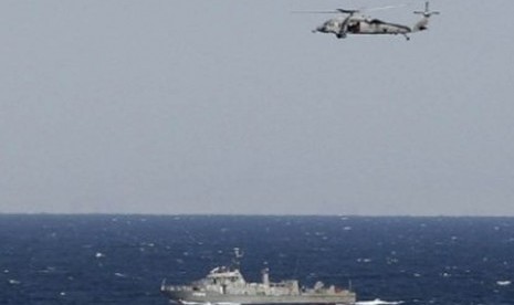 Helikopter angkatan laut AS terbang rendah di atas kapal perusak, Sterett, saat melintasi Selat Hormuz