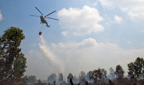  Helikopter MI 17 dari Badan Nasional Penanggulangan Bencana (BNPB) menjatuhkan bom air di atas lahan yang terbakar di Kecamatan Payung Sekaki, Kota Pekanbaru, Riau, Jumat (24/7).