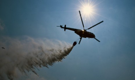 Helikopter MI 17 dari Badan Nasional Penanggulangan Bencana (BNPB) menjatuhkan bom air di atas lahan yang terbakar di Kecamatan Payung Sekaki, Kota Pekanbaru, Riau, Jumat (24/7).