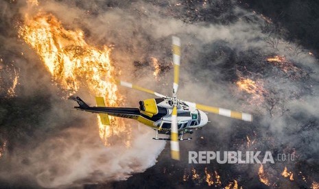 Helikopter pemadam kebakaran melintasi  api liar yang menyapu  Distrik Bel Air, California, Amerika Serikat.