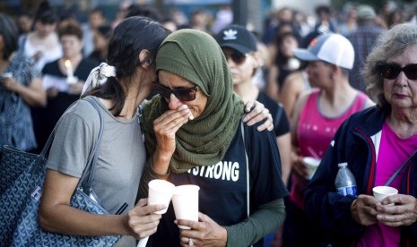 Hina Moheyuddin (kiri) menenangkan Noshaba Afzal saat acara mengenang korban penembakan di festival bawang putih Gilroy Garlic Festival, Senin (29/7) di Gilroy, Kalifornia.