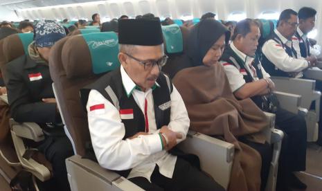 Para petugas haji Indonesia sedang melaksanakan sholat jamak berjamaah di dalam pesawat 