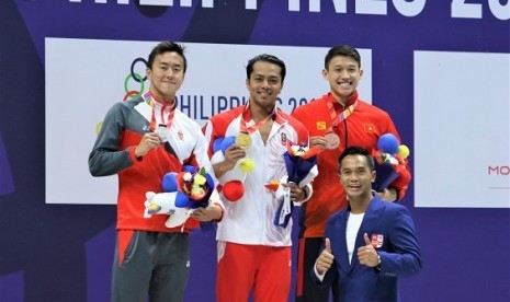 I Gede Siman Sudartawa (tengah) saat menerima medali emas renang nomor 50 meter gaya punggung putra. Indonesia mengumpulkan 11 emas di SEA Games 2019 sepanjang Sabtu.