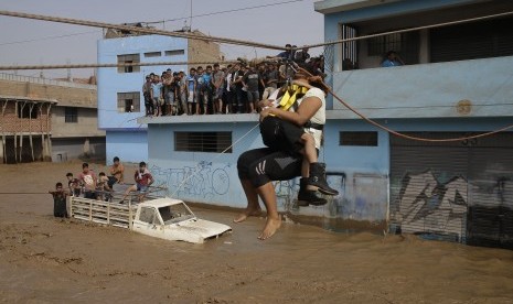 Ibu dan anaknya ditarik menggunakan tali untuk memindahkan dari tempat tempat banjir di Lima, Peru, (17/3).