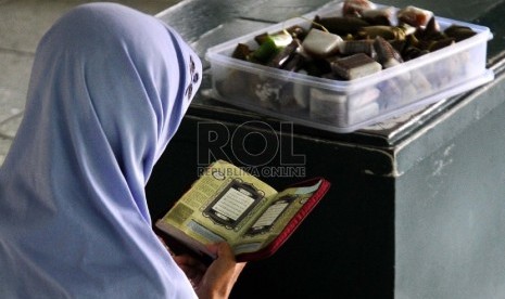 Ibu pedagang kue keliling membaca kitab suci Al-Quran di kompleks Masjid Sunda Kelapa, Jakarta, Senin (19/1). (Republika/ Tahta Aidilla)