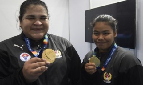 ifter Indonesia Melinda Gusti (kanan) dan Nurul Akmal menunjukkan medali emas yang mereka peroleh pada nomor angkat besi putri 75 dan +75 kg 18th Asian Games Invitation Tournament di JiExpo, Jakarta, Senin (12/2). 