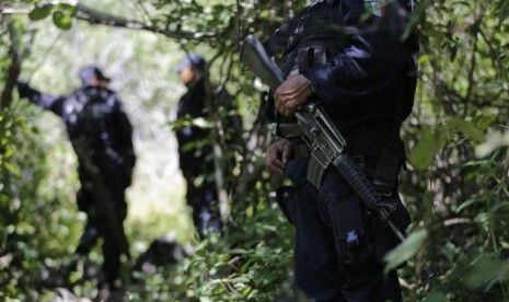 Iguala police officers stand guard at an area near clandestine graves at Pueblo Viejo, in the outskirts of Iguala, southern Mexican state of Guerrero October 9, 2014.