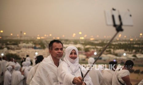 Ilustrasi jamaah melakukan foto selfie saat memakai pakaian umrah.