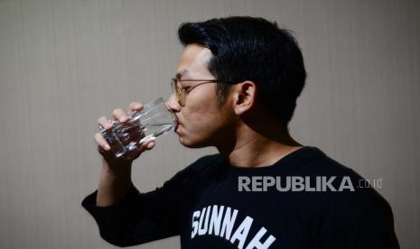 Pria minum air putih. Cegah terbentuknya batu ginjal dengan cukup minum air.