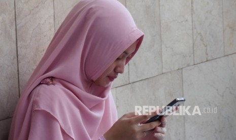 Ilustrasi Wanita berjilbab/wanita main gadget. (Republika/Darmawan)