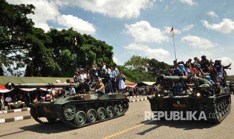 Ilustrasi Warga menumpang kendaraan tempur saat defile alutsista TNI.