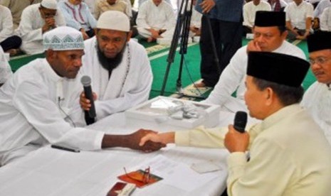 Imam Masjid Istiqlal, Ustadz Ali Hanafiah (kanan), membimbing Kepala Suku Asmat Papua, Umar Abdul Kayimter (kiri), saat membaca dua kalimat Syahadat di Masjid Darussalam, Jatibening, Bekasi, Jawa Barat, Ahad (19/2). 