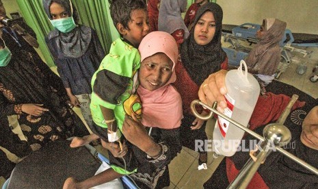 Imigran etnis Rohingya yang terdampar, Kamal Husen (8th) bersiap dibaringkan oleh ibunya saat menjalani perawatan intensif di Rumah Sakit Zubir Mahmud, Idi, Aceh Timur, Aceh, Jumat (6/4).