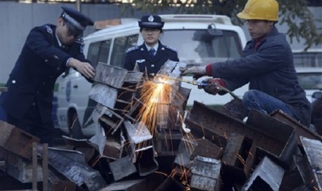 In Nov. 26 photo, municipal officers observe as a worker break down confiscated open-air barbecues confiscated in the past three months in Xicheng district in Beijing, China. (file photo)