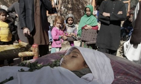 In this file photo taken Sunday, Oct. 27, 2013, relatives surround the body of a ten-year-old Afghan girl who was killed by a roadside bomb explosion on the outskirts of Kabul, Afghanistan. 