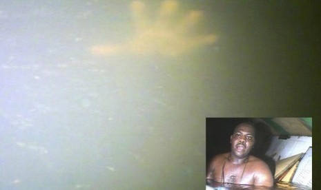 In this image made available Tuesday Dec. 3, 2013, the hand of Harrison Odjegba Okene stretches through the murky waters to reach a rescue diver as the diver's headcam video records the moment he becomes aware that Okene is still alive after nearly three d