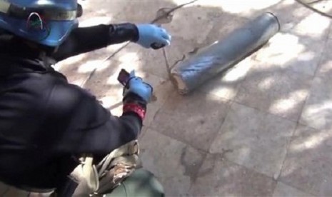 In this image taken from amateur video posted online, appearing to show a presumed UN staff member measuring and photographing a canister in the suburb of Moadamiyeh in Damascus, Syria, Monday Aug. 26, 2013.