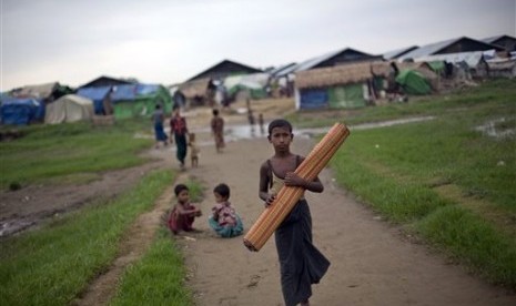 In this June 24, 2014 photo, an ethnic Rohingya boy, who was displaced following 2012 sectarian violence, walks with a mat at Dar Paing camp for refugees in north of Sittwe, Rakhine State, Myanmar.