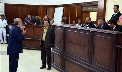 In this May 18, 2014 file photo, Muslim Brotherhood leader Mohammed Badie (left) speaks before judge after getting out of a defendant cage during his trial in Cairo, Egypt. 