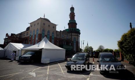 Museum London Inggris akan rekam kondisi Muslim Inggris selama pandemi. Foto diambil pada Jumat (24/4). Seorang relawan dengan mengenakan pakaian pelindung dan masker berjalan melalui parkir mobil Masjid Jamia Tengah Ghamkol Sharif, Birmingham, Inggris. 