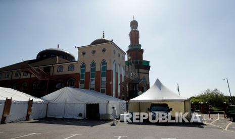 Foto diambil pada Jumat (24/4). Seorang relawan dengan mengenakan pakaian pelindung dan masker berjalan melalui parkir mobil Masjid Jamia Tengah Ghamkol Sharif, Birmingham, Inggris. Pada bulan suci Ramadhan seperti sekarang biasanya Masjid Jamia Tengah Ghamkol Sharif dipenuhi kedatangan para jamaah. Tapi tahun ini, kedatangan sebagian besar adalah orang yang mati. Sementara masjid di pusat kota Inggris di Birmingham telah ditutup sebagai reaksi terhadap pandemi coronavirus dan tempat parkirnya telah diubah menjadi kamar mayat sementara dengan kapasitas ruang untuk 150 mayat.  