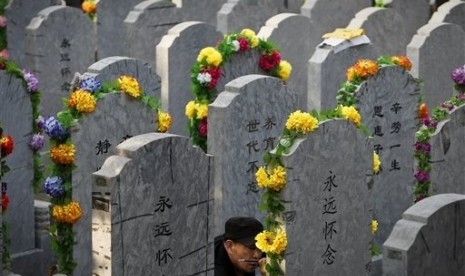 In this Tuesday, April 5, 2011 file photo, a Chinese man repaints the characters on a tomb of his deceased relative at a cemetery on the Qingming Festival in Beijing, China. 