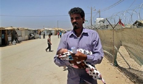 In this Wednesday, July 24, 2013 photo, Syrian refugee Ali Shteiwi holds his newborn daughter, Taymaa, at the Zaatari refugee camp in Mafraq, Jordan, near the border with Syria. 