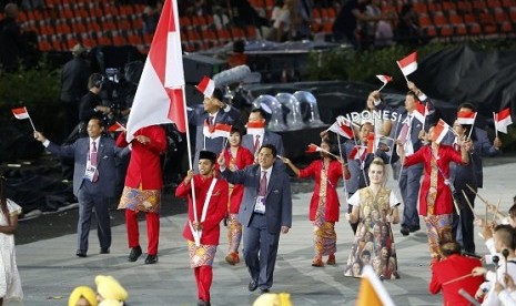 Indonesia's flag bearer Gede Sudartawa holds the national flag as he leads the contingent in the athletes parade during the opening ceremony of the London 2012 Olympic Games at the Olympic Stadium July 27, 2012. While Erick Thohir steps behind Sudartawa.  