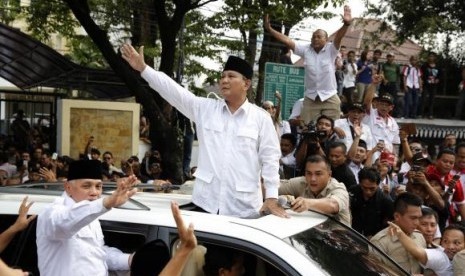 Indonesian presidential candidate Prabowo Subianto (center) and his vice presidential running mate Hatta Rajasa wave to supporters after registering at the Election Commission, May 20, 2014.