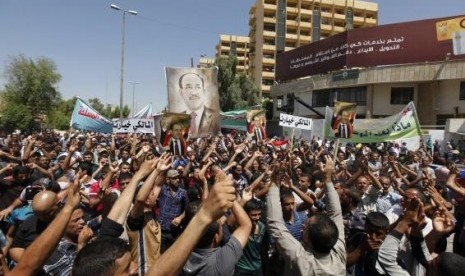 Iraqis carry portraits of incumbent Iraqi Prime Minister Nuri al-Maliki as they gather in support of him in Baghdad August 13, 2014. 