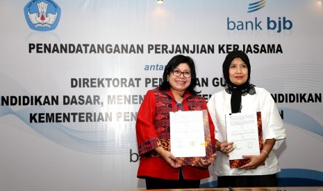 irektur Konsumer Bank BJB Fermiyanti (kiri) dan Direktur Pembinaan Guru Pendidikan Dasar Kemendikbud RI Poppy Dewi Puspitawati menunjukkan berkas perjanjian kerja sama (PKS) terkait jasa dan layanan Bank BJB untuk kalangan guru di Komplek Kemendikbud RI, J