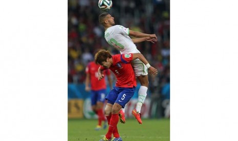 Islam Slimani (atas) dari Aljazair beraksi dengan Kim Younggwon dari Korea Selatan selama Piala Dunia FIFA 2014 grup H pertandingan babak penyisihan antara Korea Selatan dan Aljazair di Estadio Beira-Rio di Porto Alegre, Brasil,  Minggu (22/6).  (EPA/Moham