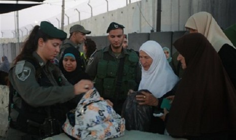 Israeli border police officers check the bag of Palestinian worshippers as they wait to cross through an Israeli checkpoint on their way to pray at the Al-Aqsa Mosque in Jerusalem, on Friday, July 12, 2013. Israel occcupies the land for more than 60 years.