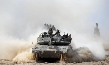 Israeli soldiers ride atop a tank outside the southern Gaza Strip July 7, 2014.