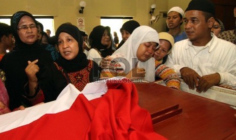  Istri almarhum Bripka Sukardi, Tirta Sari (kedua kiri) bersama putri keduanya Devi Novita (kedua kanan) berdoa di depan peti jenazah, Jakarta Timur, Rabu (11/9).  (Republika/Adhi Wicaksono)