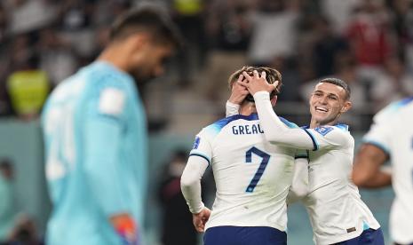 Jack Grealish dari Inggris (tengah) merayakan dengan rekan setimnya Phil Foden, kanan, setelah mencetak gol keenam timnya selama pertandingan sepak bola grup B Piala Dunia antara Inggris dan Iran di Stadion Internasional Khalifa di Doha, Qatar, Senin, 21 November 2022.