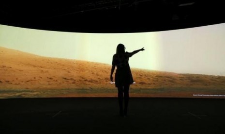 Jacqueline Storey, a press officer at the National Maritime Museum, poses for a photograph in front of images of Mars generated by NASA's Curiosity Rover at their new Visions of the Universe exhibition, in Greenwich, London June 5, 2013.