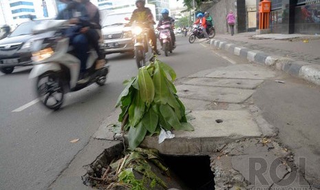 Jalan Berlubang: Pengendara melintas di samping jalan berlubang di Jalan Prapatan, kawasan Tugu Tani, Jakarta Pusat, Senin (22/12). 