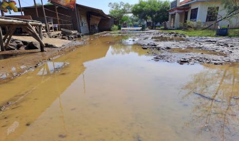 Jalan masuk menuju Pantai Karangsong, Kabupaten Indramayu, Jawa Barat, yang kondisinya becek setelah diterjang banjir rob selama tiga hari terakhir, Rabu (12/7/2023). 